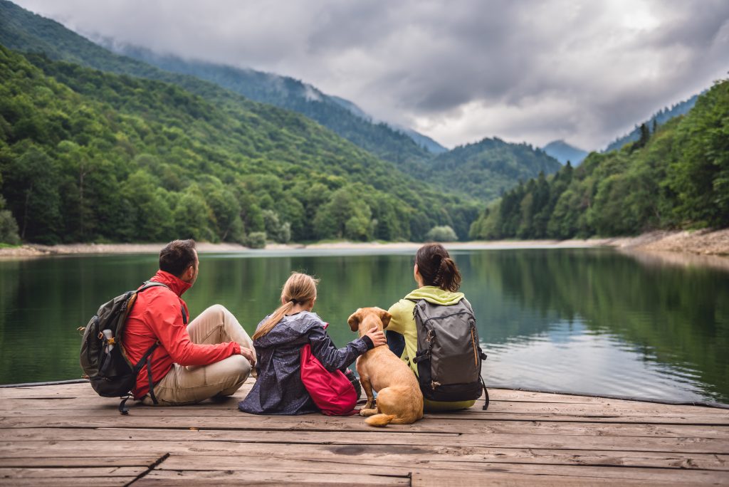 Famille et leur chien assis au bord d'un lac ayant souscrit à la protection juridique.